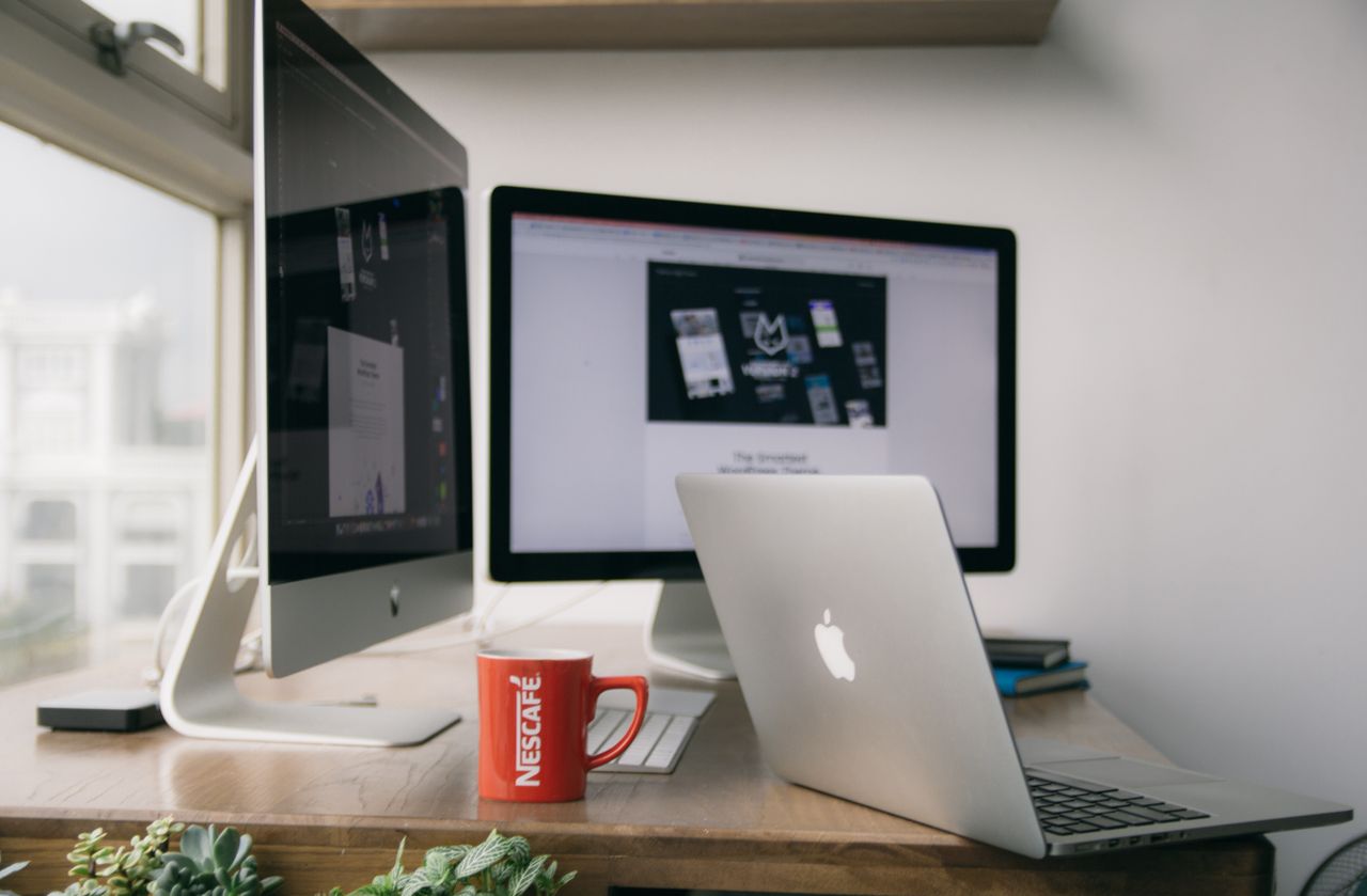 Un bureau contemporain et lumineux avec des ordinateurs et une tasse posée sur un bureau.